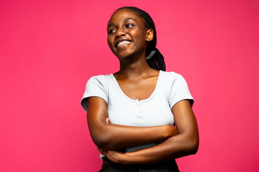 Noella Akuzwe poses in front of a pink background.